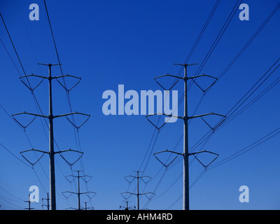 Grande potenza di torri di linea di trasporto di energia elettrica che si estende su un profondo cielo blu Foto Stock