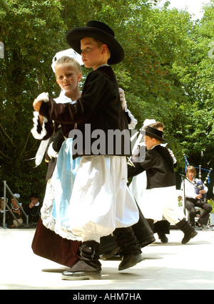 Indossando i costumi tradizionali, Breton figli eseguire un ballo folk durante un festival estivo in un villaggio bretone Foto Stock