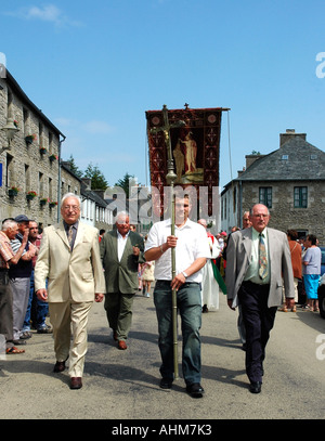 Gli uomini con una croce e banner condurre la processione in La Feuillée durante il villaggio bretone annuali di perdono, o festa religiosa Foto Stock