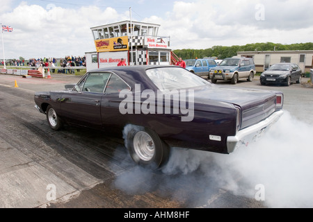 Fortemente modificati American muscle car facendo un burnout prima di un drag race Foto Stock