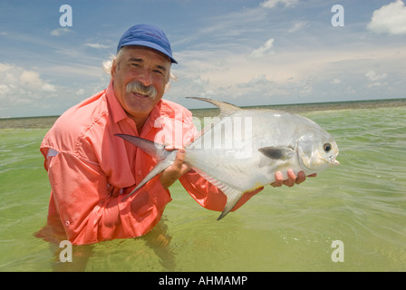 Florida Keys maturo pescatore a mosca il rilascio di un permesso di pesci catturati durante la pesca con la mosca gli appartamenti dell'oceano dei Caraibi Foto Stock