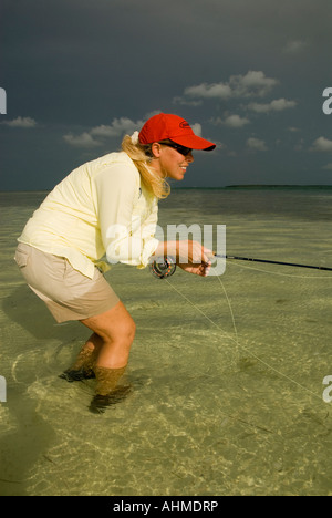 Florida Keys femmina di pesca a mosca per Bonefish mentre wading sotto cieli bui sulle parti piatte dell'oceano dei Caraibi Foto Stock