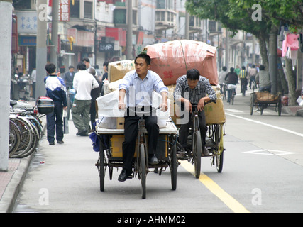 Ciclisti in risciò che trasportano merci in una speciale pista ciclabile a Shanghai, Cina Foto Stock