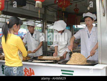 Giovane donna a una strada a base di noodle cibo stallo in Shanghai Foto Stock