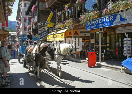 Zermatt stretta strada principale dello shopping con carro trainato da cavalli Foto Stock