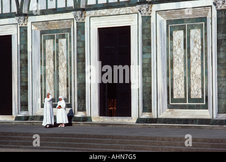 Chiesa di San Minato al Monte in Toscana città collinare a Firenze, Italia. Sacerdote e suora che parlano. Facciata in marmo verde e bianco di un edificio romanico Foto Stock