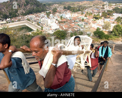 Gli operai portano un pellegrino in montagna per un santuario Foto Stock
