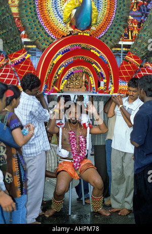 Thaipusam devoto portante un kavadi e poggiante su una sedia vicino Grotte Batu Kuala Lumpur in Malesia a sud est asiatico Foto Stock