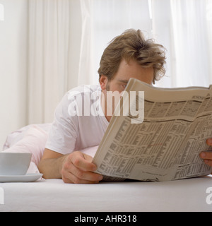 Uomo nel letto con tè e carta Foto Stock