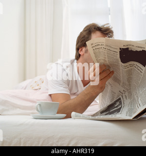 Uomo nel letto con tè e carta Foto Stock