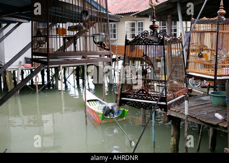 Gabbie di uccelli appendere fuori le case costruite su palafitte in mare nel Golfo di Thailandia Foto Stock