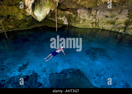 Un nuotatore galleggiante sul suo retro nei cenote " due occhi" (Messico). Homme faisant la planche dans le cénote Dos Ojos (Mexique). Foto Stock