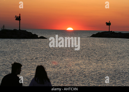 Giovane con la schiena rivolta lontano dalla telecamera, guardare un bel tramonto su un porto Foto Stock