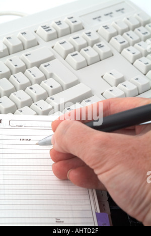Tastiera del computer con una mano e blocco note Foto Stock