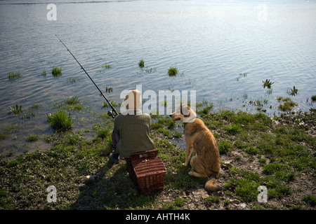 Ragazzo (12-14) la pesca di fiume con cane da compagnia, vista posteriore Foto Stock