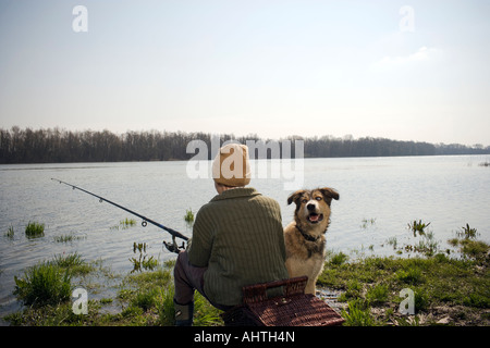 Ragazzo (12-14) la pesca di fiume con cane da compagnia, vista posteriore Foto Stock