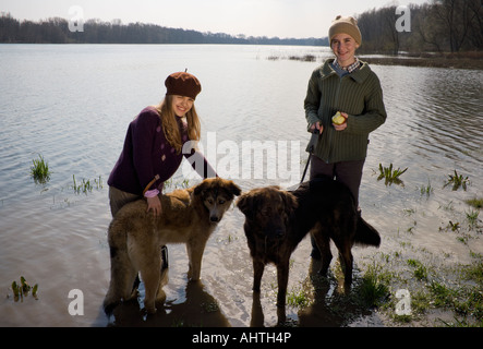 Fratello (12-14) e sorella (11-13) in piedi nel fiume con due cani, sorridente Foto Stock