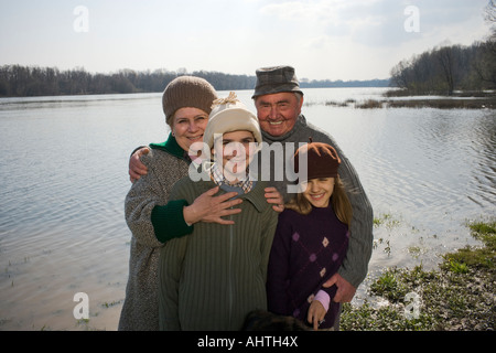 Nonni in piedi accanto al fiume con il nipote (12-14) e grangdaughter (11-13) sorridente Foto Stock