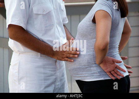 Navale militare marito mette le mani sullo stomaco della moglie incinta Foto Stock
