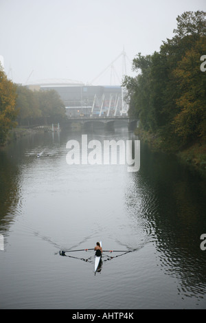 L'uomo canottaggio sul fiume Taff superato il Millennium Stadium di Cardiff Foto Stock