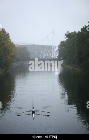 L'uomo canottaggio sul fiume Taff di Cardiff in distanza il Millennium Stadium può essere visto Foto Stock