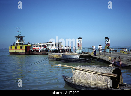 Un veicolo e un traghetto passeggeri che scappano al molo e le case galleggianti sul fiume Jamuna. Bangladesh Foto Stock