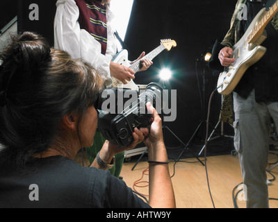 Fotografo femmina a due riprese la chitarra elettrica i giocatori in studio vicino. Foto Stock