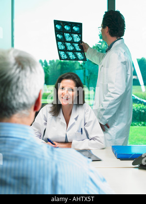 Due medici a discutere di raggi x con matura paziente. Foto Stock
