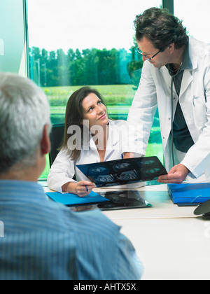 Due medici a discutere di raggi x con matura paziente. Foto Stock