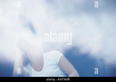 Giovane donna utilizzando il telefono cellulare con le riflessioni di nuvole. Foto Stock