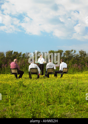 Gruppo di imprenditori seduti su sedie in campo. Foto Stock