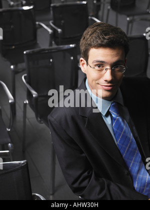 Ritratto di giovane uomo seduto in auditorium Foto Stock