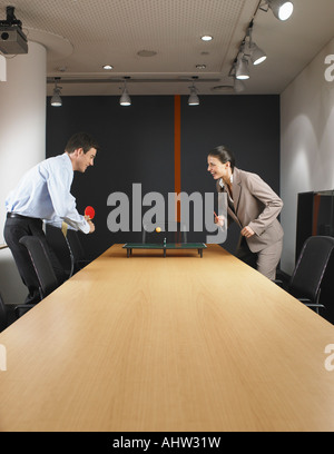 L uomo e la donna in miniatura a giocare a ping pong al tavolo della sala riunioni Foto Stock