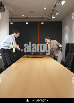 L uomo e la donna in miniatura a giocare a ping pong al tavolo della sala riunioni Foto Stock