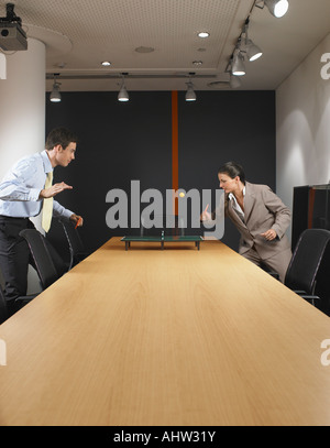 L uomo e la donna in miniatura a giocare a ping pong al tavolo della sala riunioni Foto Stock