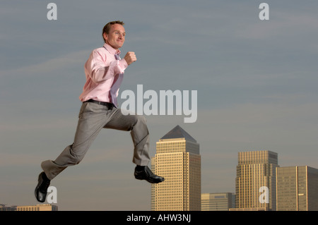 Businessman jumping nella parte anteriore del paesaggio urbano Foto Stock