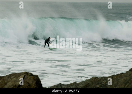 Surfer cavalcare un onda a Newquay, Cornwall Foto Stock