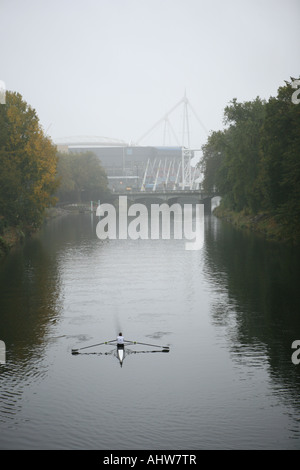L'uomo canottaggio sul fiume Taff superato il Millennium Stadium di Cardiff Foto Stock