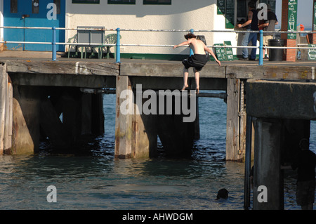 Un ragazzo salta in mare dal molo a Weymouth Dorset, nel Regno Unito - un letale craze noto come 'tombstoning'. Foto Stock