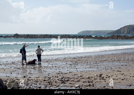 Giovane su una spiaggia a guardare un ^surfer Foto Stock