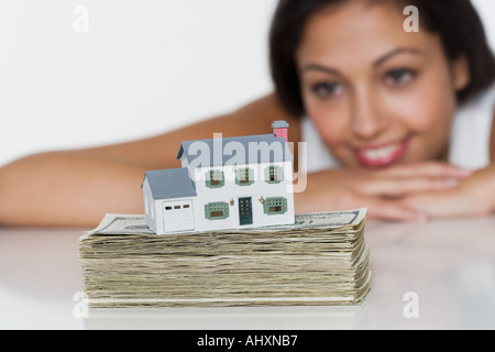 Donna con casa in miniatura e denaro Foto Stock