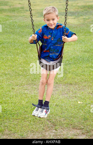 Sette anni di vecchio ragazzo gioca su uno swing Foto Stock