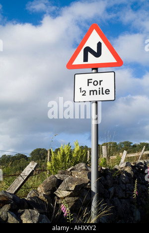 Dh triangolo rosso segni cartello stradale Regno Unito di orientamento per strada tortuosa strada curva per 1/2 miglia segno paese di avvertenza e attenzione Foto Stock