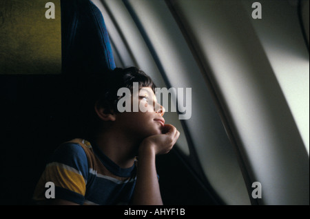 Giovane ragazzo caucasico guardando fuori della finestra piano Foto Stock