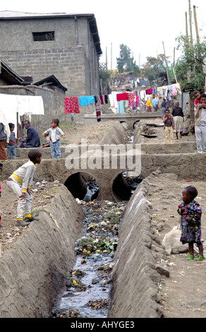 Bambini che giocano accanto a fogne aperte in una zona di baraccopoli ad Addis Abeba. Etiopia Foto Stock