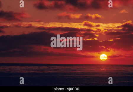 Tramonto sull'oceano La grande giallo sole dà un bagliore arancione per le nuvole del cielo e del mare Foto Stock