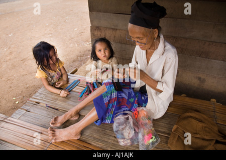 I bambini e gli anziani donna fare braccialetti per vendere i turisti in Hmong villaggio tribale vicino a Luang Prabang, Laos Foto Stock