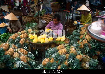 Peeling donna ananassi in un mercato Vinh Long, Vietnam. Foto Stock