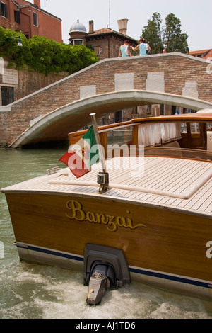 Bandiera Italiana vola da poppa di entrobordo fuoribordo taxi d'acqua vicino al ponte sul Canal Venezia Italia Foto Stock