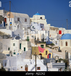 Bianco e le case dai colori pastello clustered contro un luminoso cielo blu al villaggio di Oia a Santorini isola le isole greche - Grecia Foto Stock